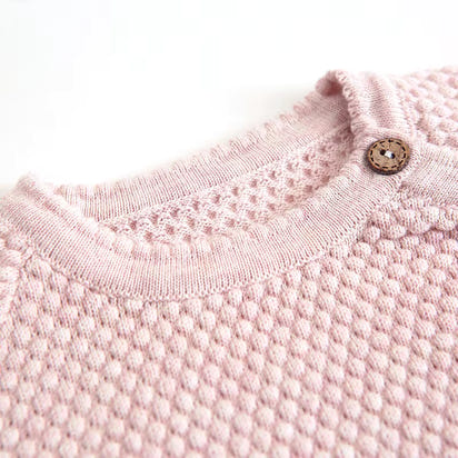 Close-up of a pink textured garment with a button on a white background
