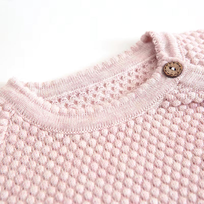 Close-up of a pink textured garment with a button on a white background
